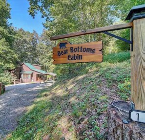 Ein hölzernes Schild mit der Aufschrift 'Bear Bottoms Cabin' und einer Bärensilhouette.