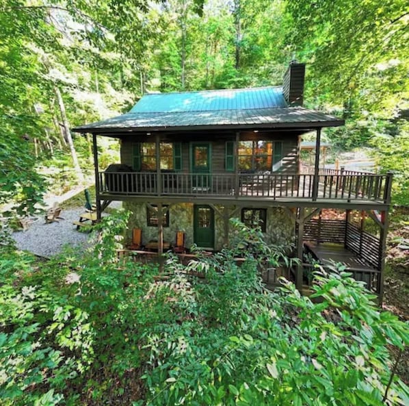 Ein rustikales Blockhaus mit grüner Dachdeckung, umgeben von dichtem Wald.