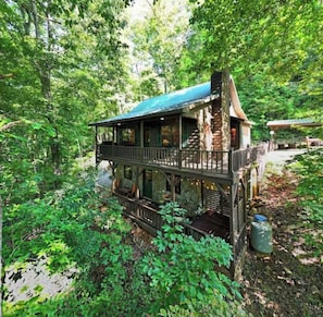 Ein rustikales Blockhaus mit Balkon, umgeben von dichtem Wald.