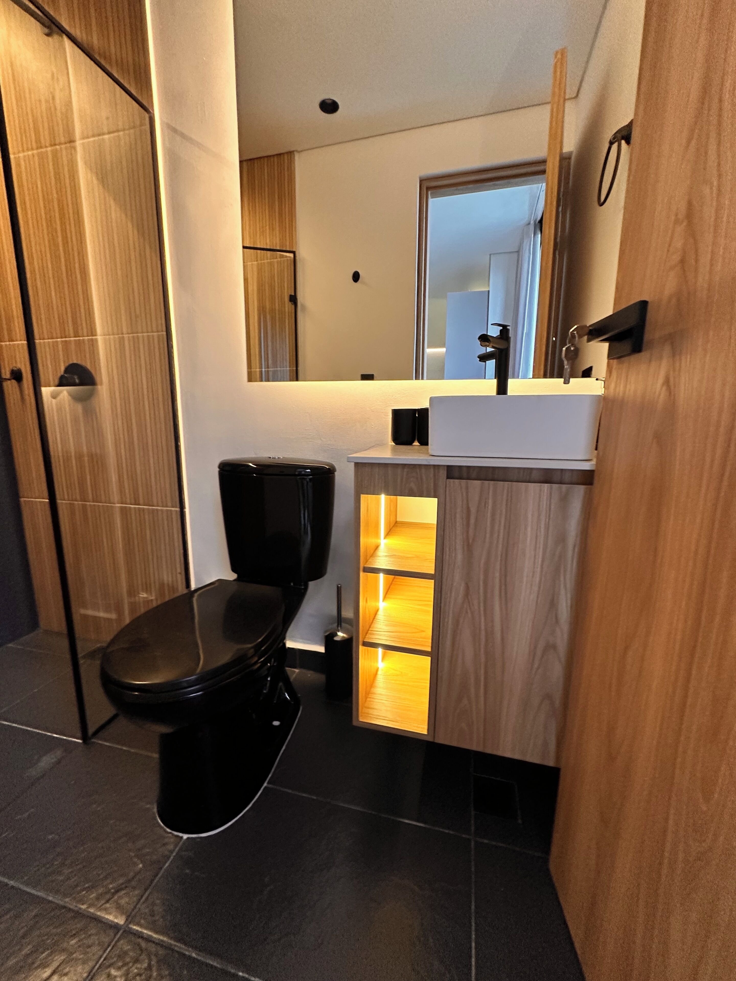 Un bagno moderno con il water, un lavandino e uno specchio.