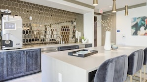 A modern kitchen with a central island, a coffee machine, and a decorative hexagonal wall. - Landing Furnished Apartments Allen - Twin Creeks (Allen)