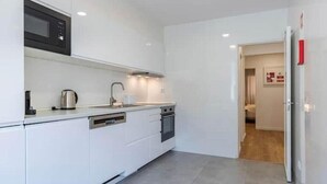 A modern kitchen with white cabinetry, a microwave, a kettle, and a dishwasher. - Village Carcavelos II - Refuge with private backyard 7 minutes from the beach (Carcavelos)