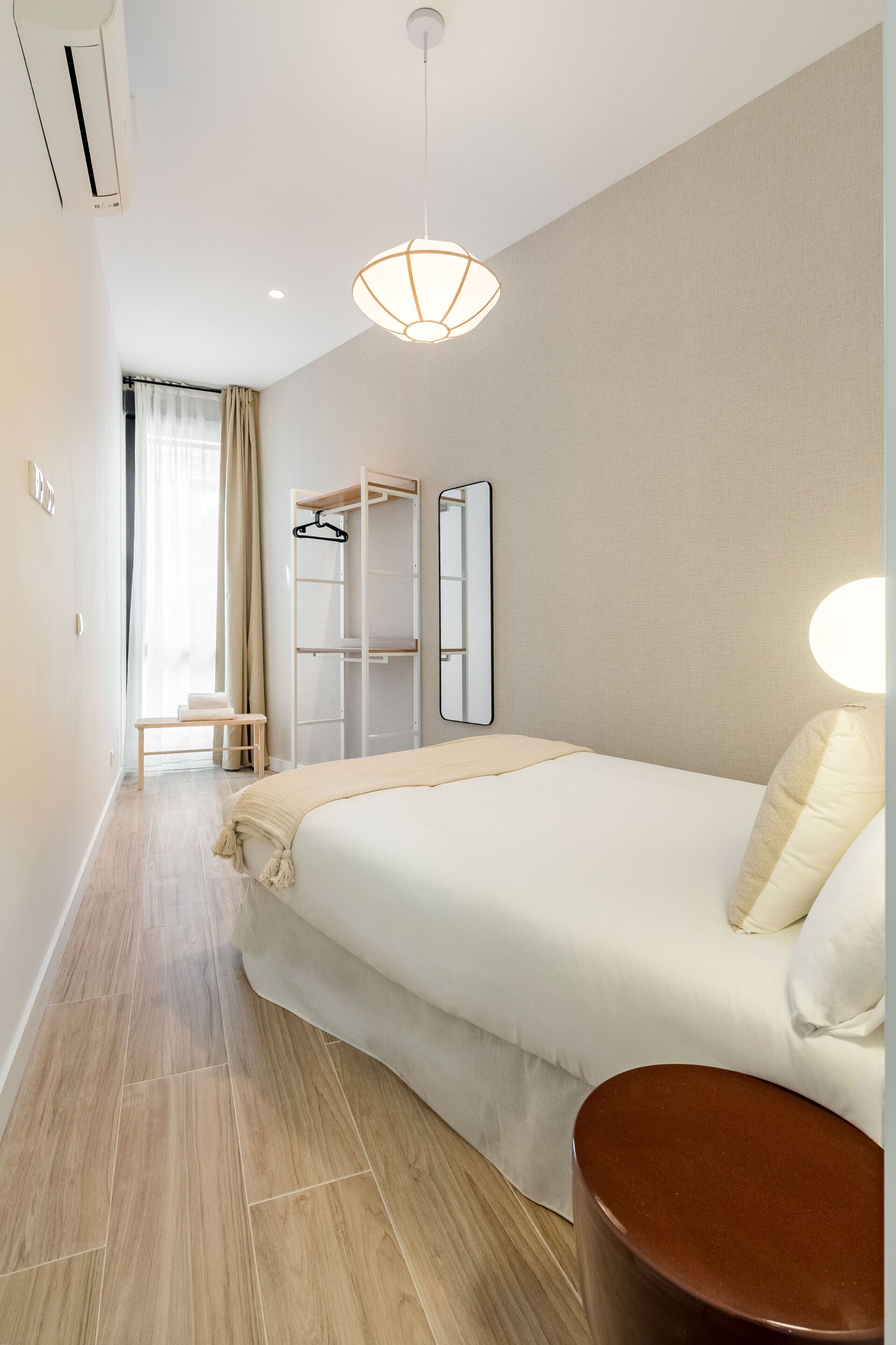 Une chambre d’hôtel comprenant un lit, une table de chevet, un porte-vêtements et un miroir.
