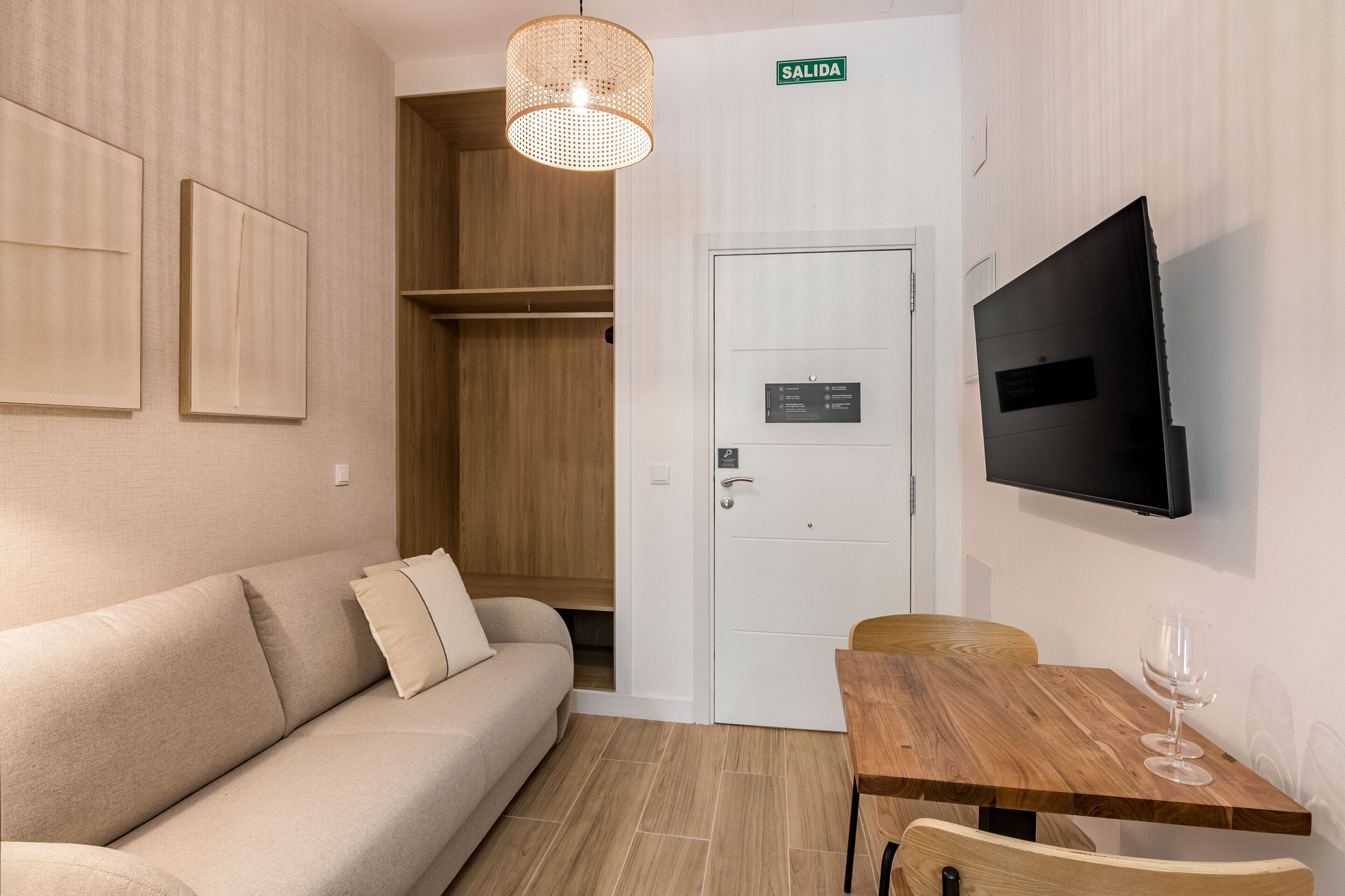 Una habitación con un sofá, una mesa de madera, un televisor y una puerta con la leyenda 'SALIDA'.