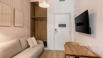 Una habitación con un sofá, una mesa de madera, un televisor y una puerta con la leyenda 'SALIDA'.