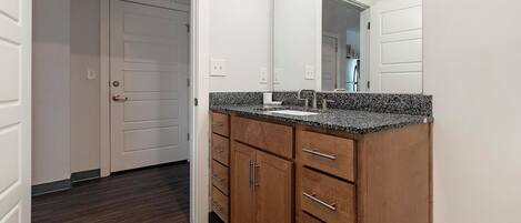 A bathroom with a wooden vanity, a sink, and a mirror.