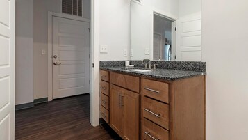 Un baño con tocador de madera, lavamanos y espejo.