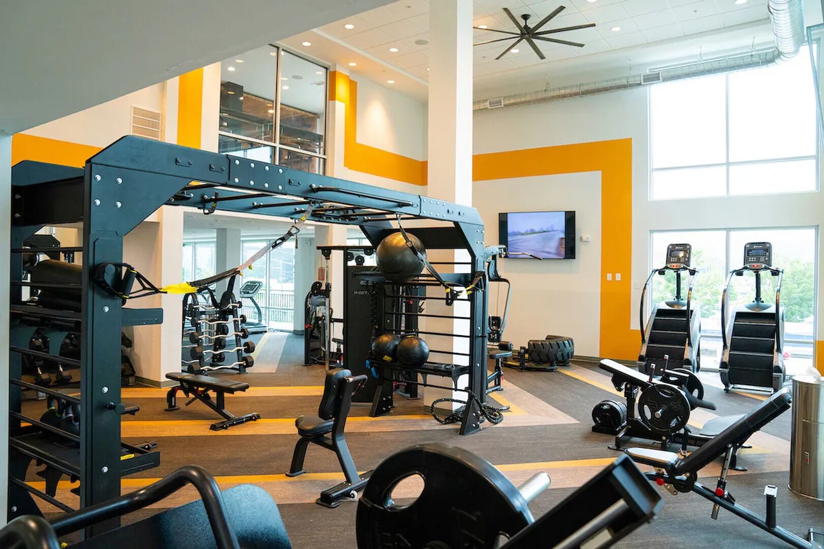 A gym with various exercise equipment, including weight machines, treadmills, and a squat rack.