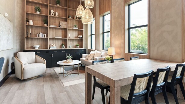 Una cocina moderna con armarios de madera, una mesa de comedor con sillas y lámparas colgantes.