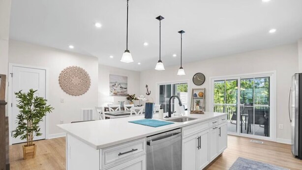 A modern kitchen with a central island, pendant lighting, and a view to a balcony. - Luxe Dye Estates Townhome @ Barefoot - Golf, Pool, Hot Tub (North Myrtle Beach)