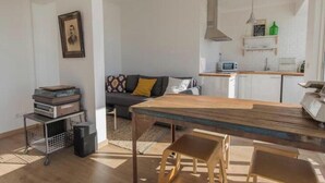 Een moderne woonkamer met een houten eettafel, een bank en een keuken met een magnetron.