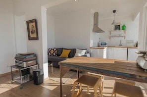 Ein modernes Wohnzimmer mit einem Holzespeisetisch, einer Couch und einer Küchenzeile inklusive Mikrowelle.