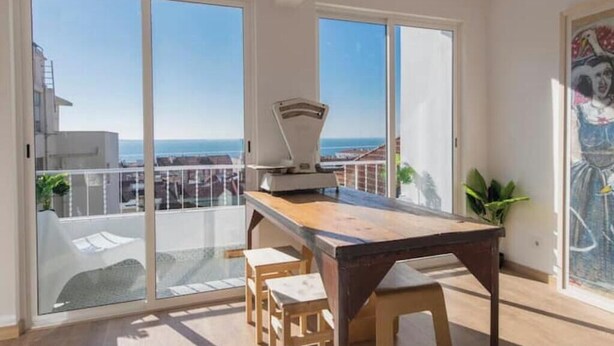 Een balkon met uitzicht op zee, een tafel met stoelen en een schilderij aan de muur.