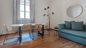 Una habitación con una mesa de comedor, sillas, un sofá, una lámpara de pie y un espejo redondo en la pared.