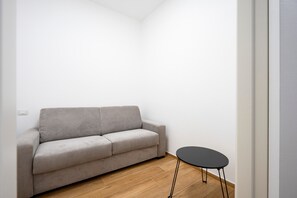 Une pièce avec un canapé gris et une petite table noire.