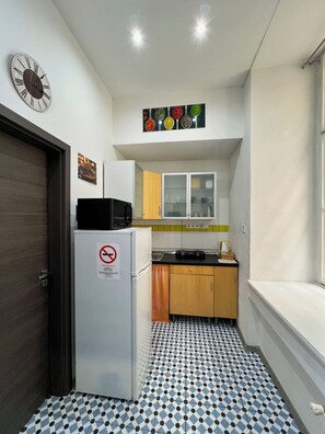 A compact kitchen with a refrigerator, microwave, and cabinets. - Cozy Loft Retreat by Chain Bridge – Stunning Danube & Parliament Views (Budapest)