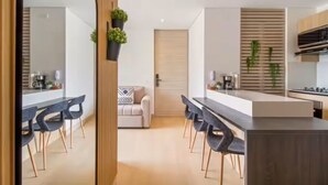 Eine moderne Küche mit einer zentralen Kochinsel, schwarzen Stühlen, einer Couch und einer Holztür.