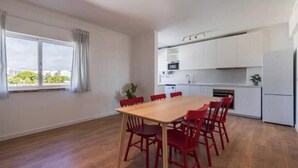 Una cucina moderna con mobili bianchi, un tavolo da pranzo con sedie rosse e un'ampia finestra con tende.