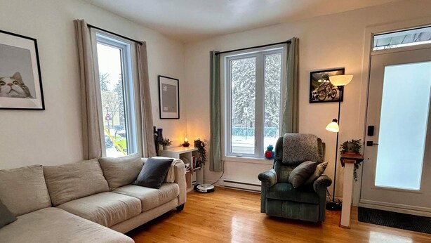 En stue med sofa, lænestol og et lille bord med lampe.