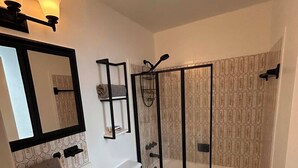 Et badeværelse med hvid vask, toilet og brusekabine.