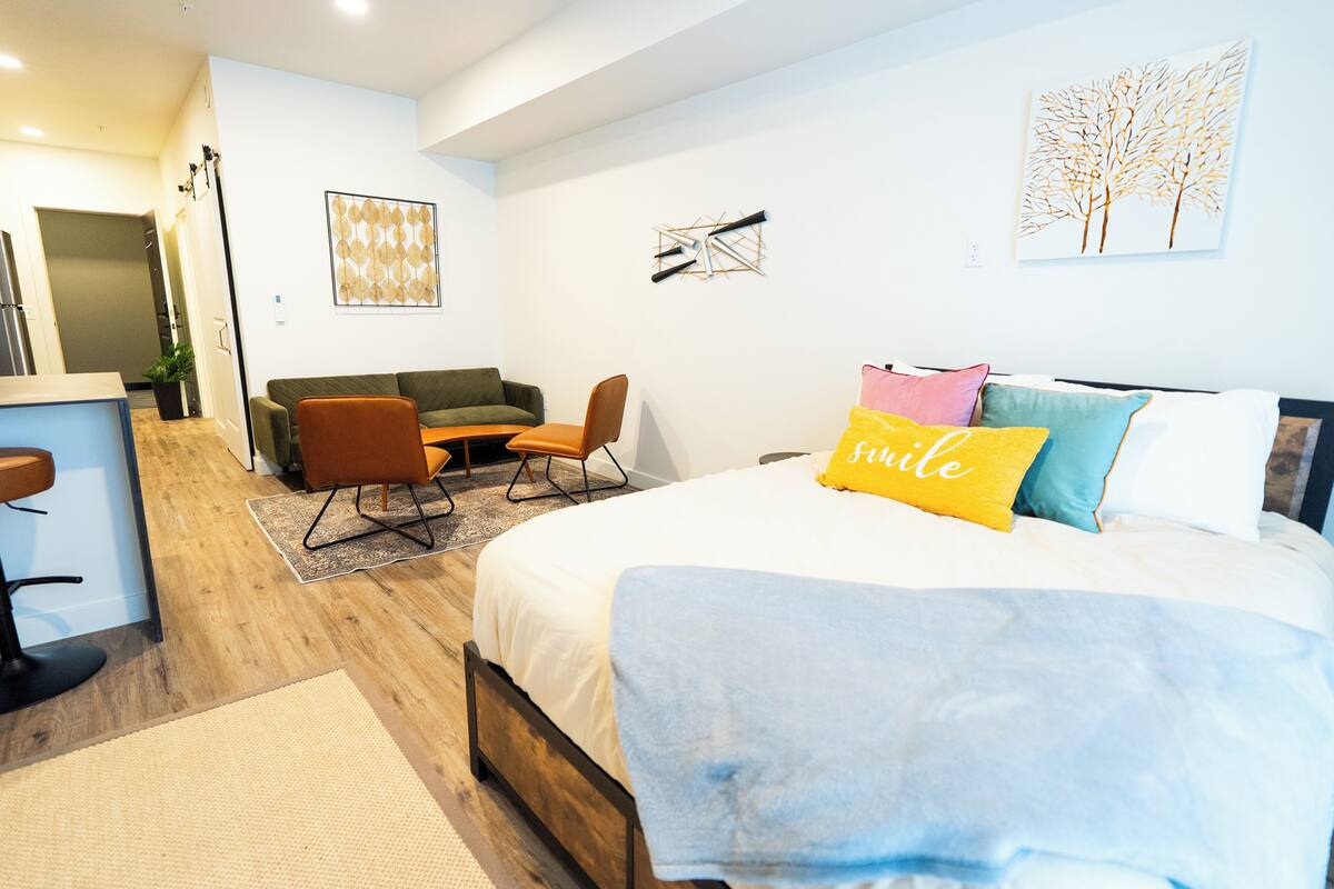 A modern bedroom with a bed, a sofa, a chair, and a desk.