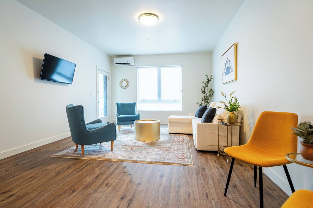 A modern living room with a flat-screen TV, a round coffee table, and a sofa.
