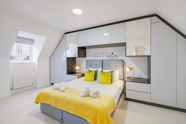 Une chambre à coucher avec un lit, une fenêtre, un radiateur et une étagère fixée au mur.