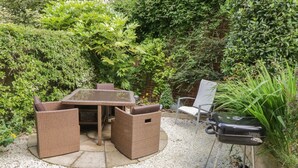 Eine Terrasse mit Tisch, Stühlen, einem Grill und einer Feuerstelle.