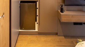 Un dormitorio moderno con cama, televisor integrado, armario y un mueble pequeño.