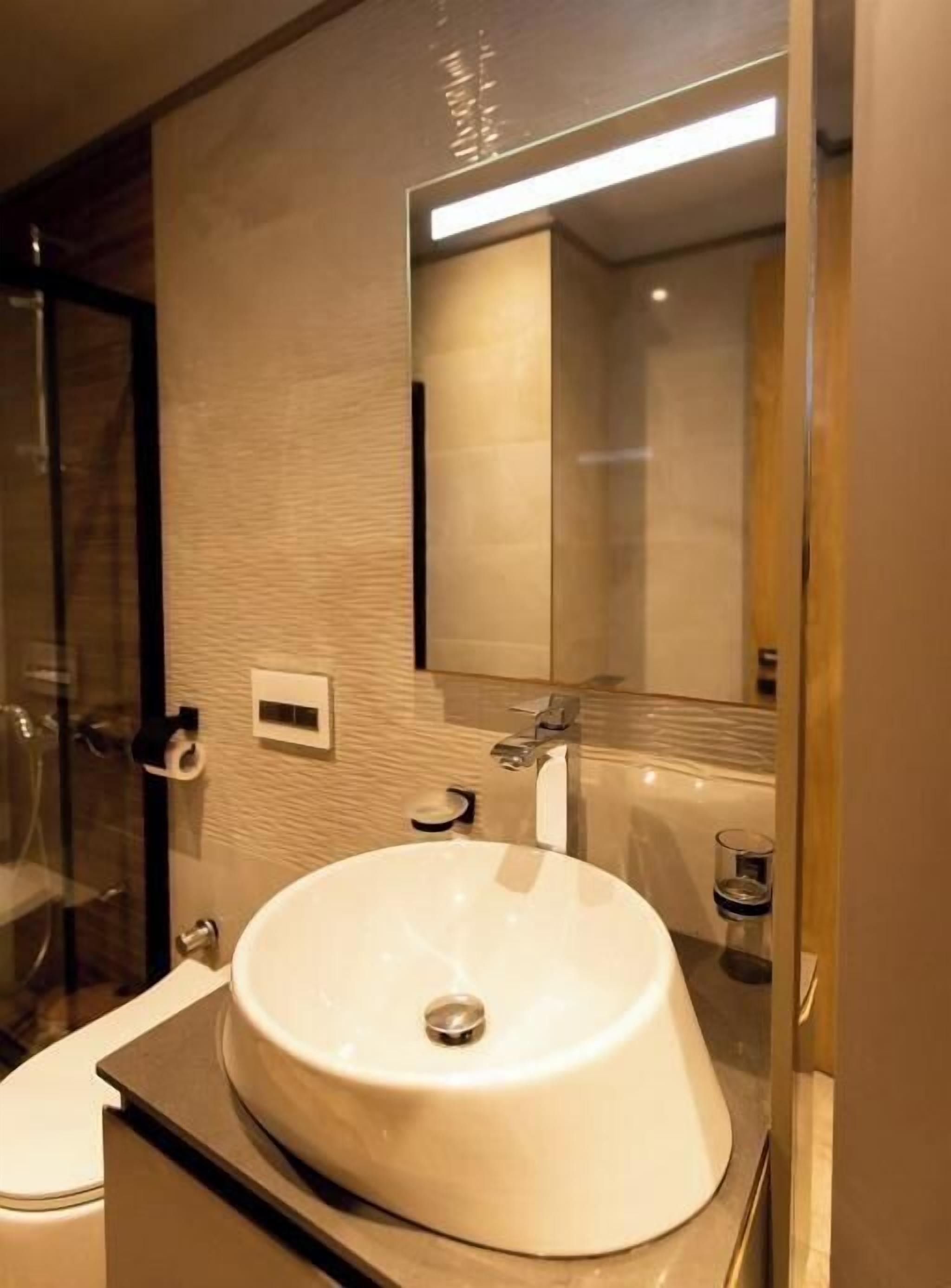 A modern bathroom with a large sink, a mirror, and a glass shower enclosure.