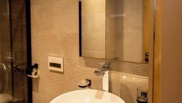 A modern bathroom with a large sink, a mirror, and a glass shower enclosure.