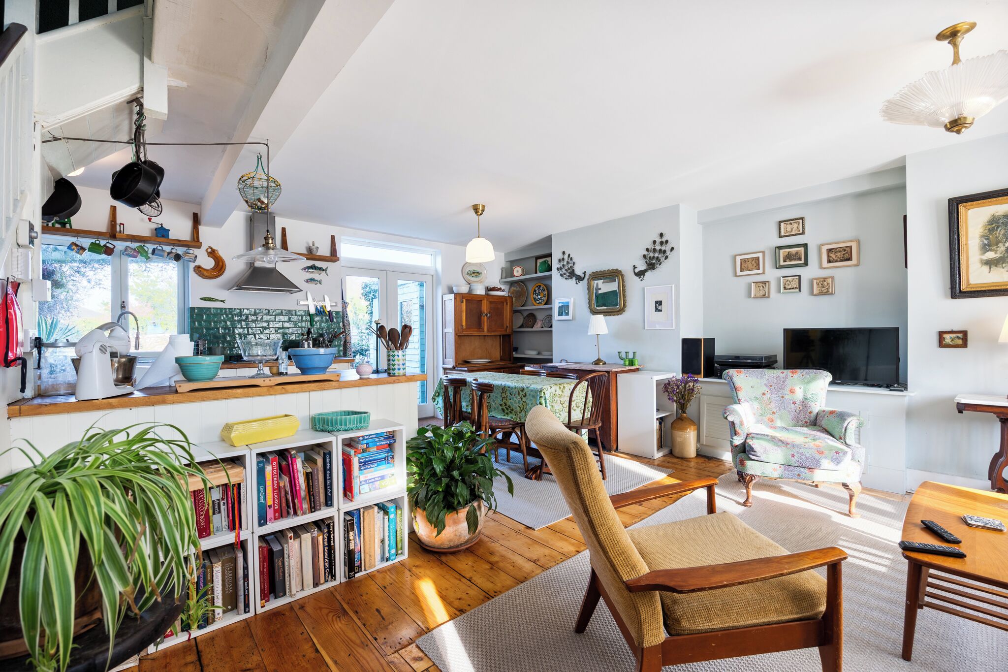 A spacious living area with a dining table, a comfortable armchair, and a bookshelf filled with books.