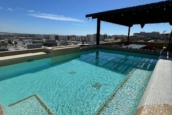 A clear swimming pool with a view of the cityscape in the background. - Lugar hermoso, cómodo y céntrico. ¿Algo más? (Cabo San Lucas)