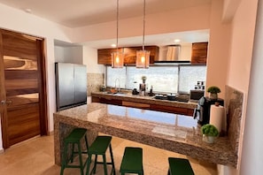 A modern kitchen with granite countertops, stainless steel appliances, and wooden cabinetry. - Lugar hermoso, cómodo y céntrico. ¿Algo más? (Cabo San Lucas)