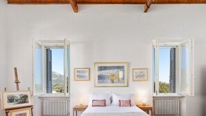 Quarto com uma cama, duas mesas de cabeceira, um radiador e três quadros na parede.
