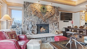 A living room with a stone fireplace, leather furniture, and a television mounted on the wall. - Lodge Tower 578 2BR at the base of Vail Mountain (Vail)