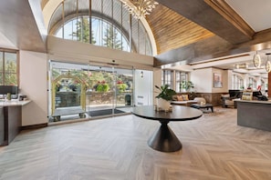 A spacious lobby with a large round table, a reception desk, and a view of the outdoors through a glass door. - Lodge Tower 578 2BR at the base of Vail Mountain (Vail)