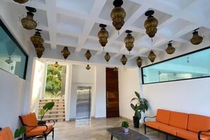 Eine Lobby mit modernem Deckenstil, einer Sitzecke mit orangefarbenen Sofas und einem großen Fenster.