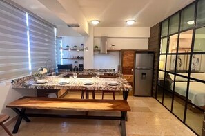 Eine moderne Küche mit Marmorarbeitsplatte, einer hölzernen Bank und einem Einbaukühlschrank.