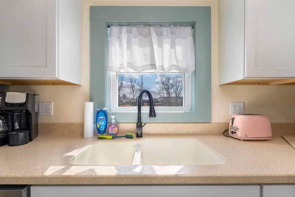 A kitchen with a window, a sink, a toaster, and a coffee maker.