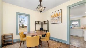 A dining area with a round table, four chairs, a chandelier, a painting, and a view through a window. - Steps to Ariel Park / Renovated 2BR Retreat (Mount Vernon)