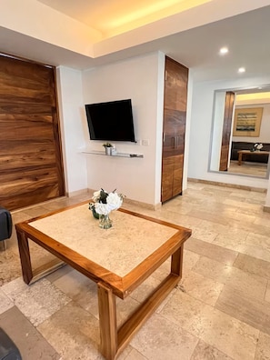 Ein modernes Wohnzimmer mit Couchtisch aus Holz, einem flachbildfernseher an der Wand und einem Holzschrank.