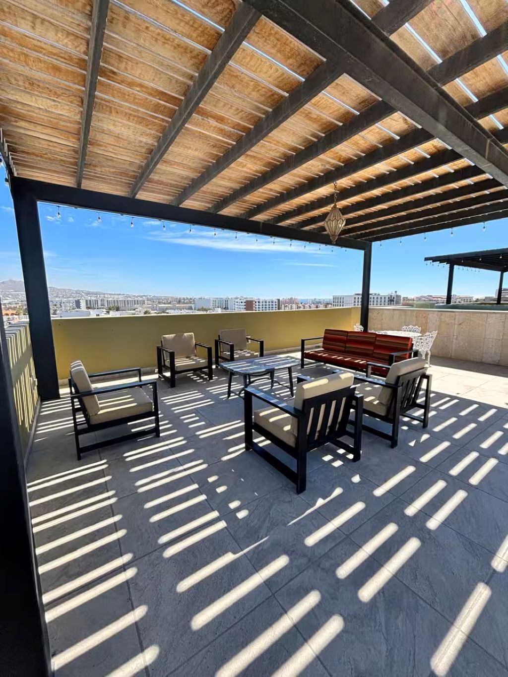 Una terrazza sul tetto con arredi da esterno, una pergola e vista sulla città.