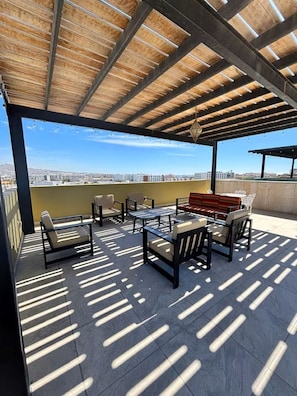 Eine Dachterrasse mit Gartenmöbeln, einer Pergola und Blick auf die Stadt.