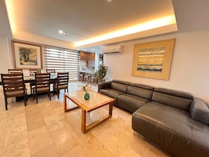 Ein Wohnzimmer mit einer Couch, einem Couchtisch und einem Essbereich mit Stühlen und einem Tisch.