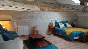 Um quarto aconchegante com uma cama, um sofá, uma mesa pequena e um radiador.