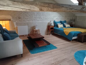 Et hyggeligt værelse med en seng, en sofa, et lille bord og en radiator.