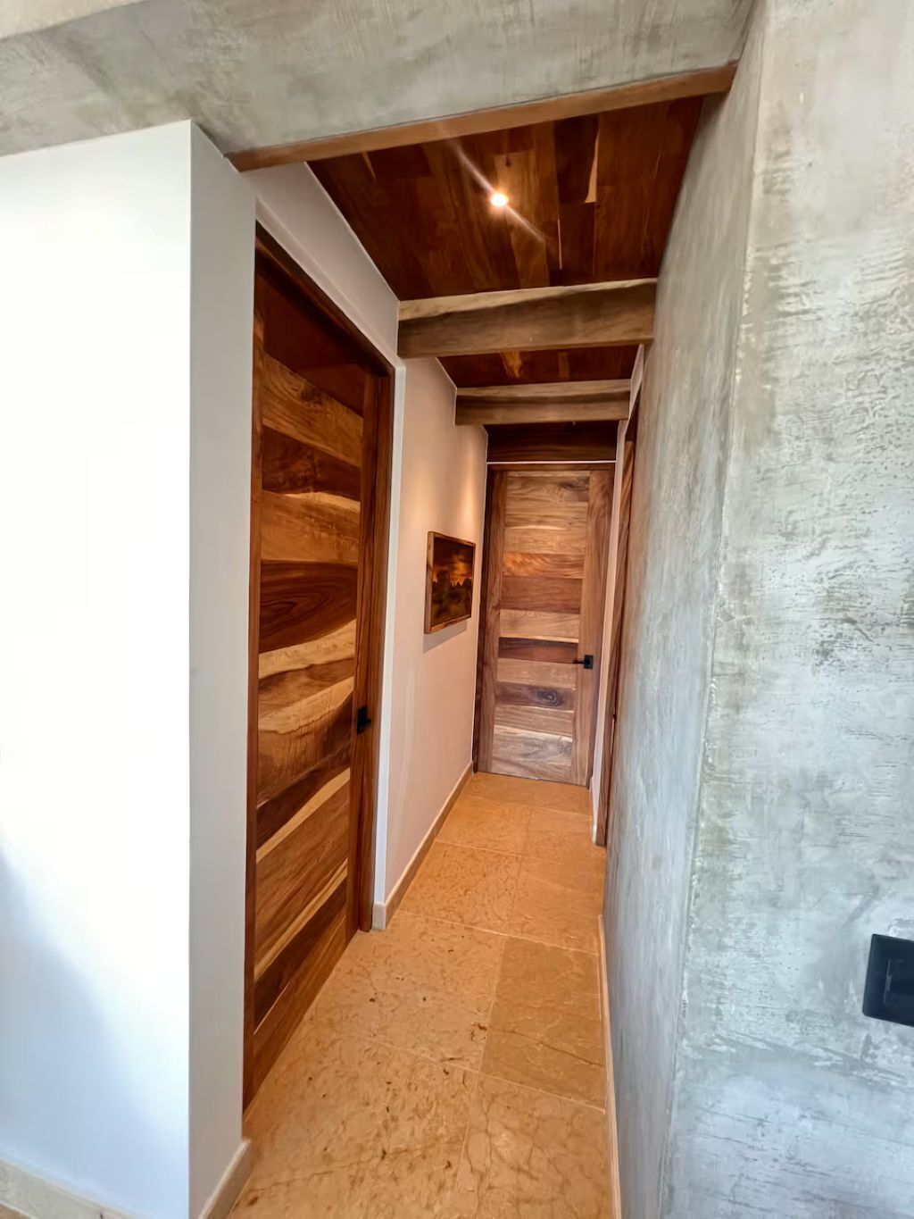 A narrow hallway with wooden doors and a textured wall.