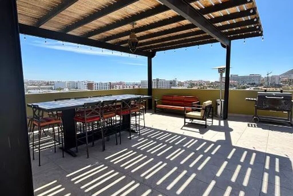 Une terrasse extérieure avec une table et des chaises, un barbecue et une vue sur le paysage urbain.