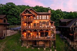A multi-story wooden cabin with balconies, large windows, and a stone foundation. - Pool/HotTub/GameRoom/Theater/FirePit/VIEWS - Coal Camp Lodge (Sevierville)